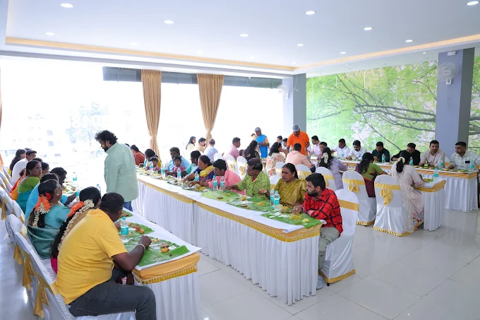Guests seated at dressed tables for a meal served on banana leaves